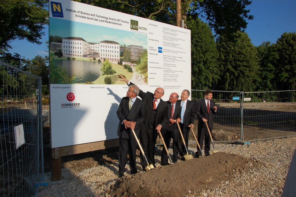 People using shovels in front of a sign, breaking ground for a new campus
