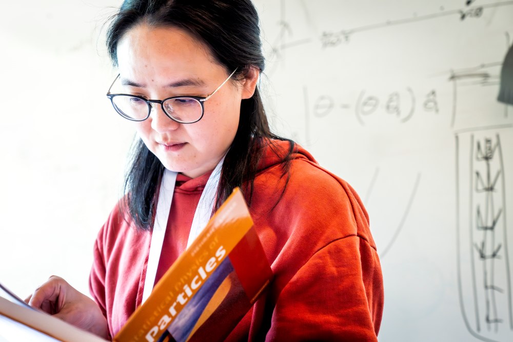 ISTA postdoc Mengjie Zu consults Mehran Kardar’s textbook, Statistical Physics of Particles.
